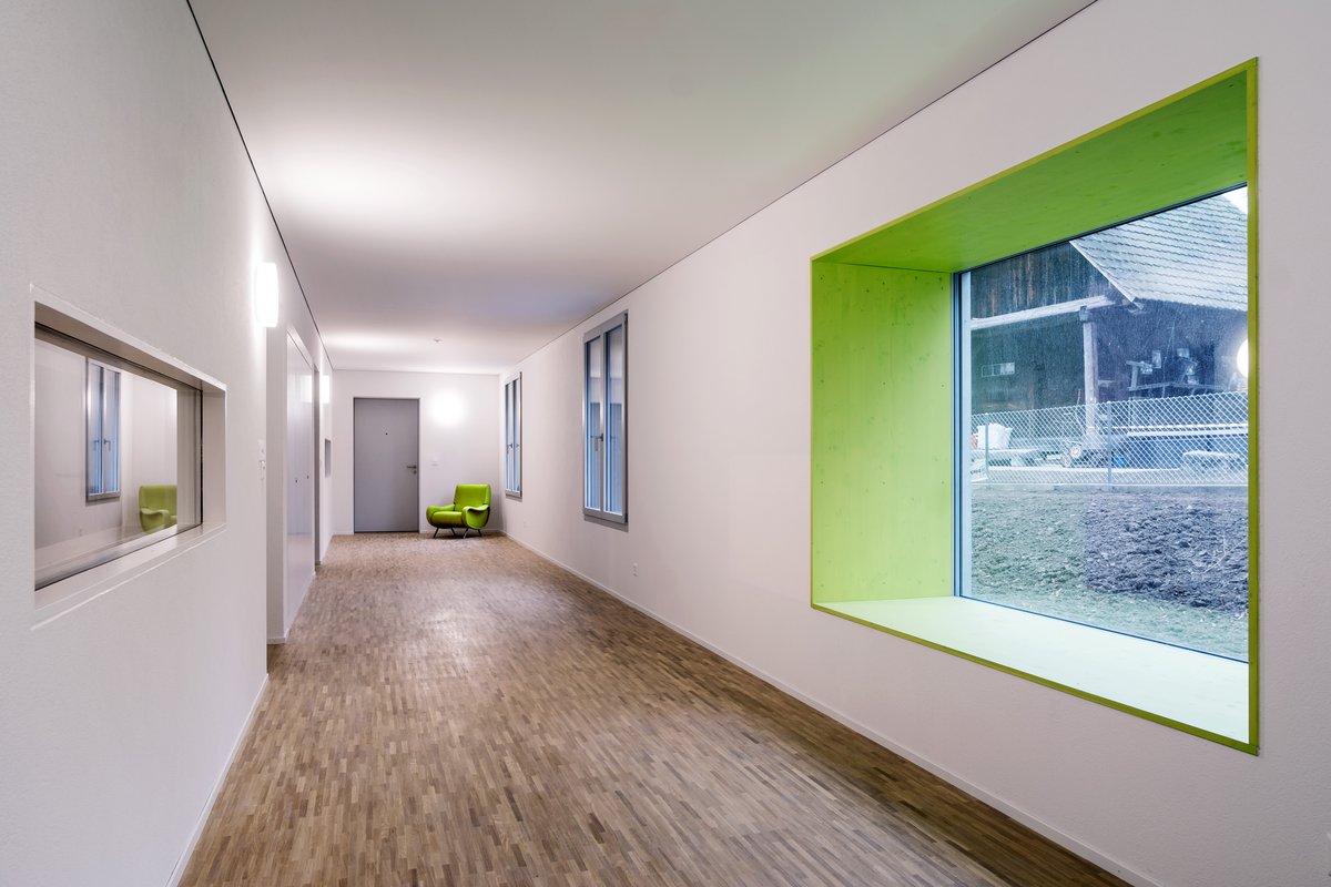 Couloir lumineux avec de grandes fenêtres comme zone de rencontre pour les habitants de 4 étages